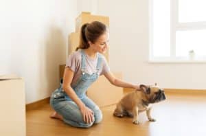 Happy Woman With Dog And Boxes Moving To New Home P42Er66